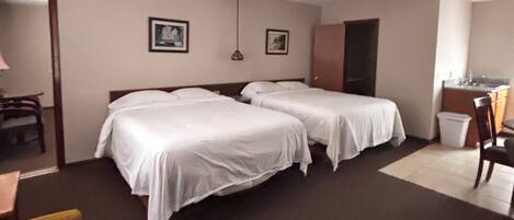 A hotel room with two beds, a desk, and a chair.