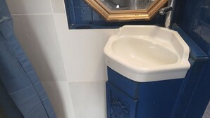 A bathroom with a white sink, blue cabinet, and a mirror with a gold frame. - Studio in a Charente-style house (Saint-Romain-de-Benet)