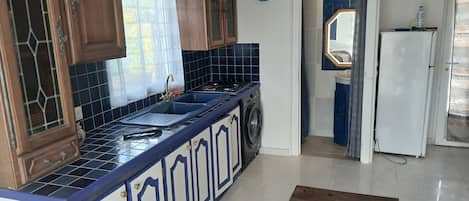 Une cuisine avec des meubles de rangement en bois, un évier, une cuisinière et un réfrigérateur.