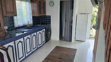 Een keuken met een wasmachine, een klok en een koelkast.