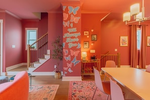 Ein Zimmer mit Treppe, Essbereich und Wand mit Schmetterlingsdekor.