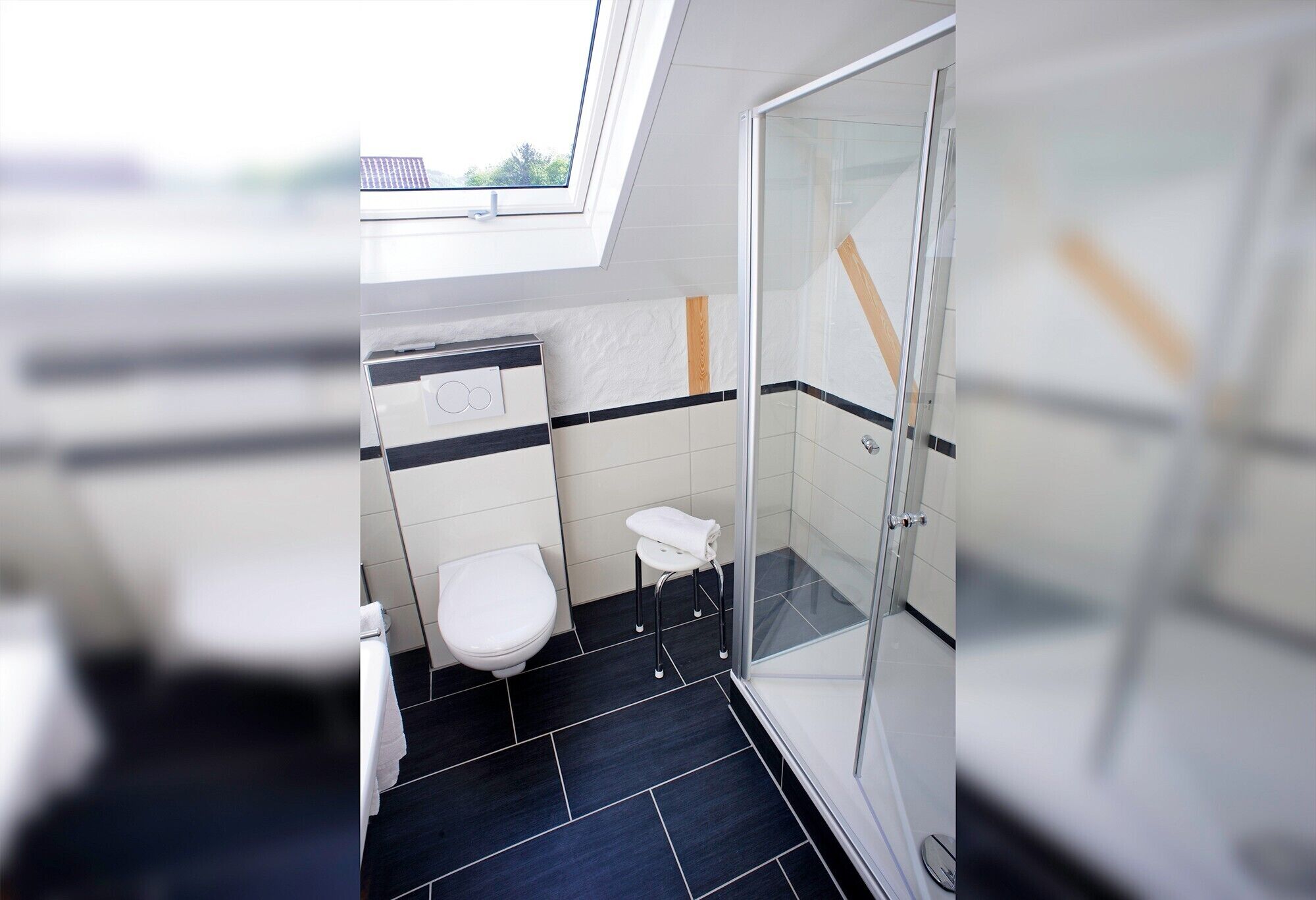 Une salle de bain moderne dotée d’un puits de lumière, d’une douche en verre et de toilettes blanches.