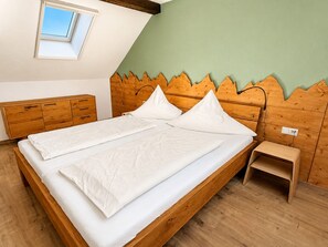 A bedroom with a wooden bed, a small bedside table, a nightstand, a window, and a sloped ceiling. - Double Room 'Traminer' with Breakfast, Free Wi-Fi & Parking, Near City Center (Gengenbach)