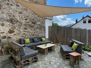 Un espace extérieur aménagé avec des sièges, un mur en pierre, des meubles en bois et une clôture en bois.