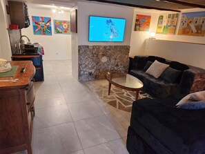 Ein Wohnzimmer mit einer Steinwand, einem Flachbildfernseher und Kunstwerken an den Wänden.