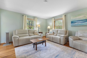 A living room with two sofas, a coffee table, and a painting on the wall.