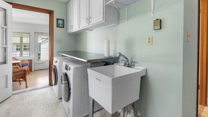 Un espace buanderie comprenant un lave-linge, un sèche-linge et un évier.