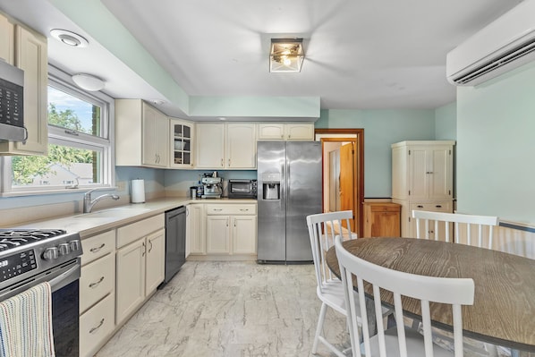 A kitchen with white cabinets, a stainless steel refrigerator, a microwave, and a stove.