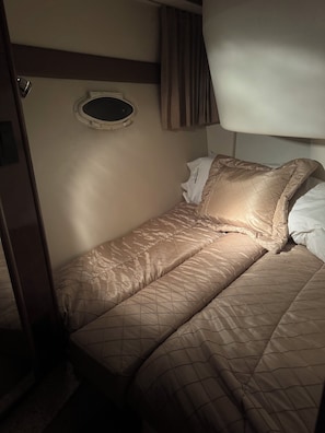 A single bed with a quilted cover, a bedside table, and a window with curtains. - AJ‘s Yacht of Fun
Two bedroom luxury 35 foot Yacht (Clearwater)