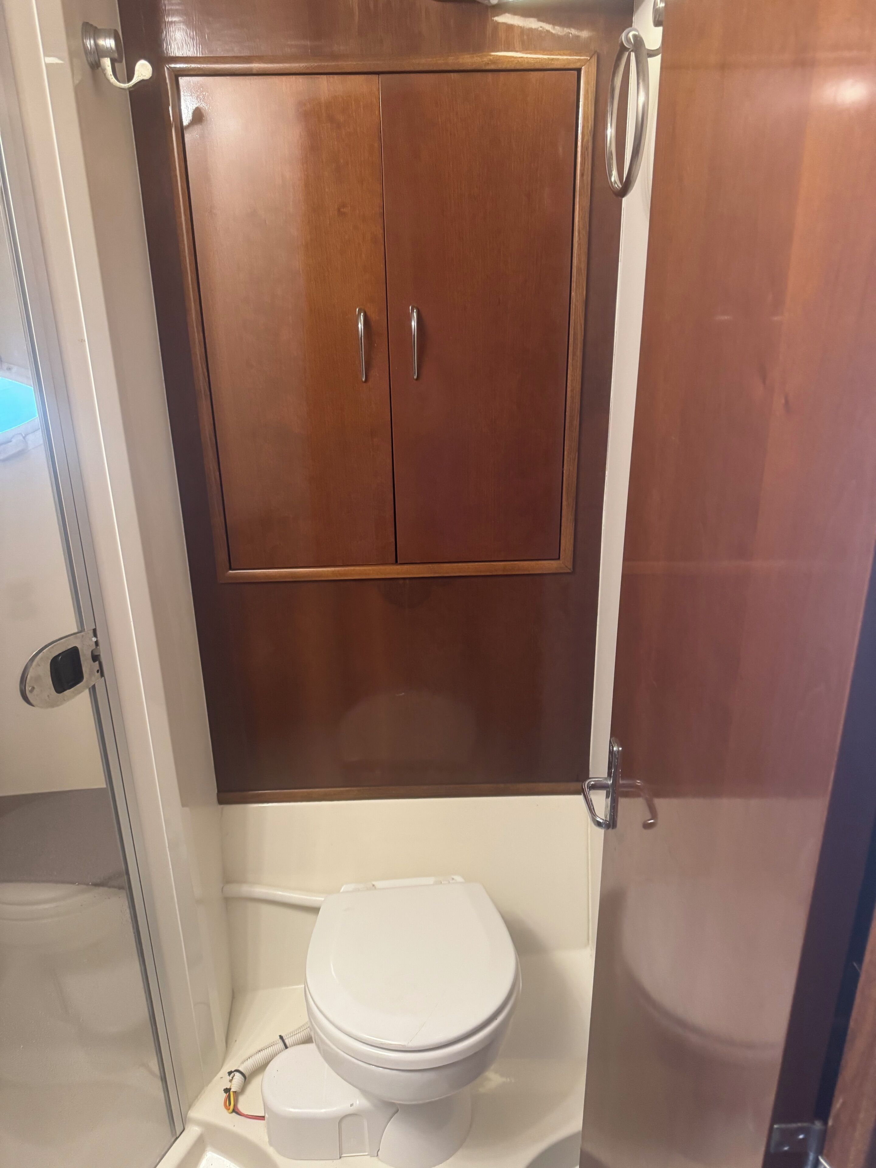 Un baño con un mueble de madera, un inodoro blanco y una zona de ducha.