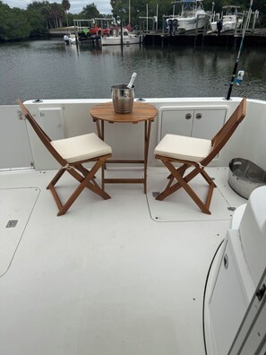 A boat's deck with two wooden chairs, a small table, and a metal bucket. - AJ‘s Yacht of Fun
Two bedroom luxury 35 foot Yacht (Clearwater)