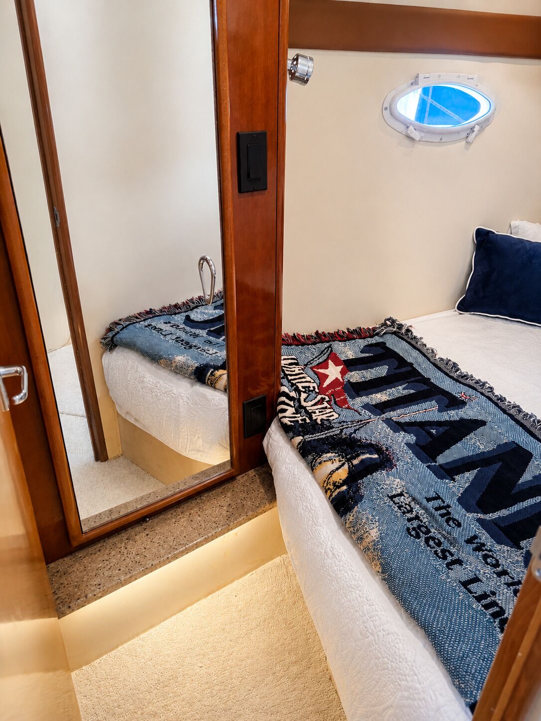 Ein kleines Schlafzimmer mit Bett, einem Fenster und einem Spiegel, der den Raum widerspiegelt.