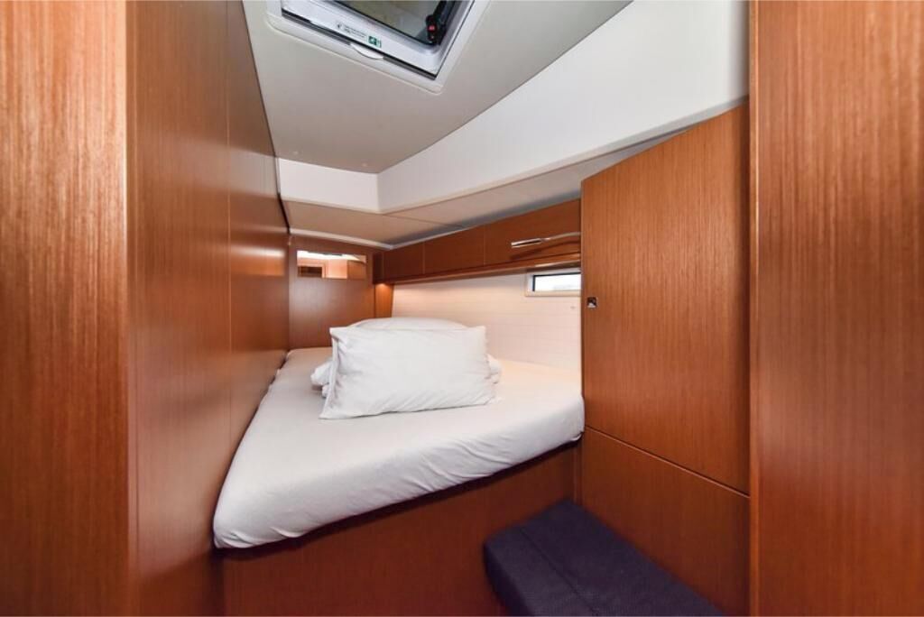 A compact cabin with a single bed, a skylight, and wooden walls.