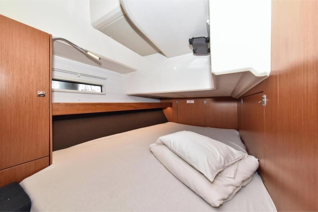 Ein kleines Blockhäuschen mit einem Einzelbett, einem kleinen Fenster und einem fest installierten Waschbecken.