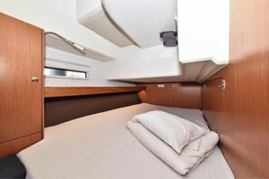 A compact cabin with a single bed, a small window, and a built-in sink. - Bavaria Cruiser 46 - Paola (Dalmacija Marina)