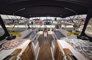 A boat deck with seating, a steering wheel, and ropes.