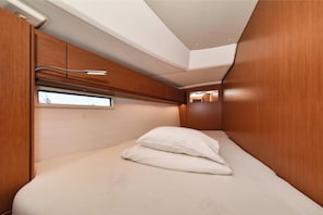 A compact, well-lit room with a bed, a window, and wooden paneling.