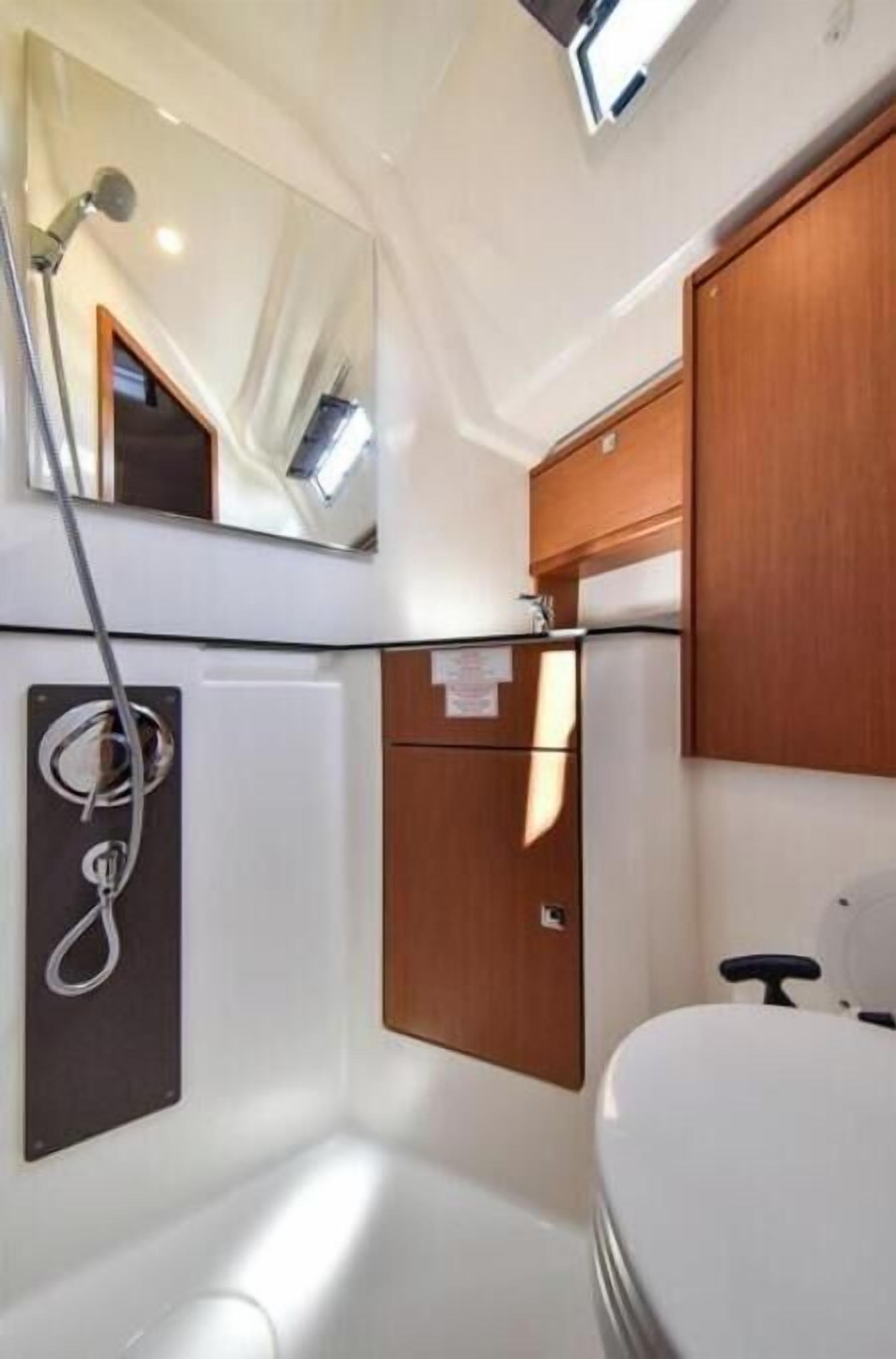 A compact bathroom with a shower, a toilet, and a mirror.