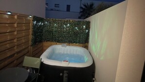 Ett bubbelbad i ett litet utomhusområde med ett trästaket och ett bord.