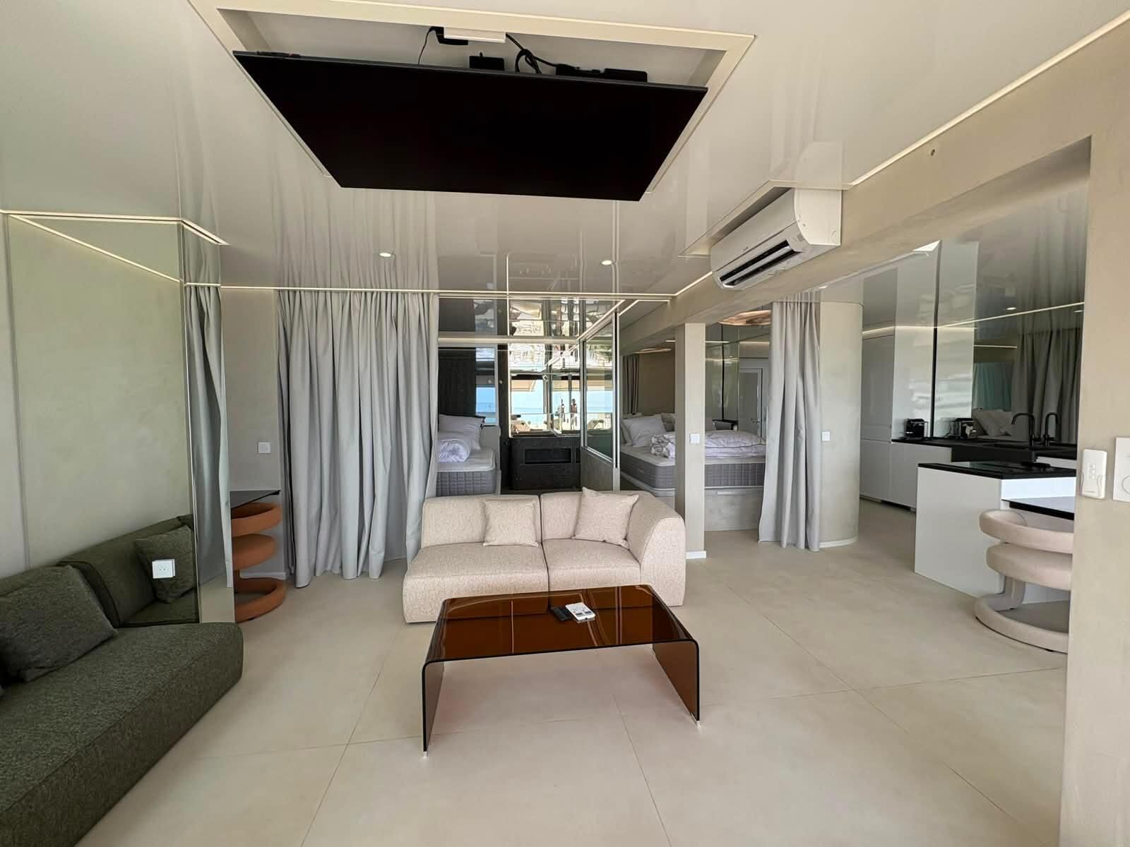 A modern living room with a sofa, a glass coffee table, and a TV.