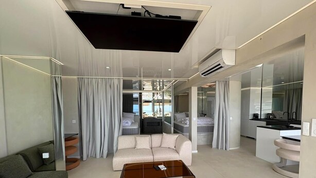 A modern living room with a sofa, a glass coffee table, and a TV. - Spacious 3-Bedroom Apartment in a Naturist Village with Ocean Views (Agde)