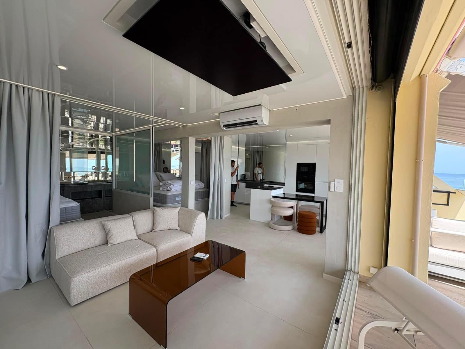 Una sala de estar moderna con un sofá, una mesa de centro y vista al mar a través de grandes ventanales.