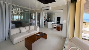 A modern living room with a sofa, a coffee table, and a view of the sea through large windows. - Spacious 3-Bedroom Apartment in a Naturist Village with Ocean Views (Agde)