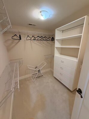 Ein begehbarer Kleiderschrank mit offenen Regalen, einem Wäscheständer und einem weißen Stauraum.