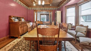 Una sala da pranzo con un lungo tavolo in legno, sedie, un armadietto in legno e un tappeto decorato.