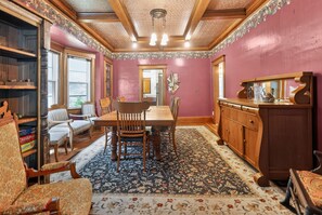 A dining room with a wooden table and chairs, a patterned rug, and a wooden cabinet. - Widder Haus, 1909 Historic Home with Porches & BBQ (Kansas City)