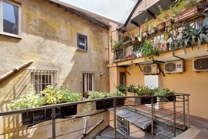 A courtyard with a metal staircase, potted plants, and a building with a yellow facade. - Navona - Charming apartment for 4 in the historic Palazzo Massimo (Roma)