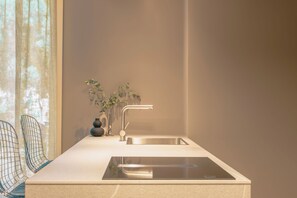 A modern kitchen with a stainless steel sink, a vase with a plant, and wire chairs. - Amber: A spectacular view in the heart of Riccione. (Riccione)