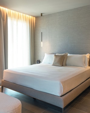A modern hotel room with a large bed, a nightstand, and a wall-mounted light. - Amber: A spectacular view in the heart of Riccione. (Riccione)