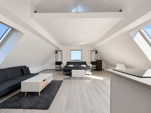 Ein modernes Schlafzimmer im Loft-Stil mit einem großen Bett, einem Schreibtisch und einer Couch.