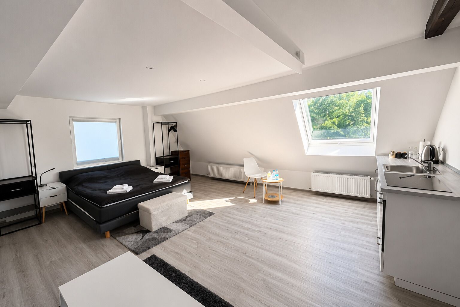 Ein modernes Schlafzimmer mit einem Bett, einem Nachttisch und einem kleinen Tisch mit Flaschen.