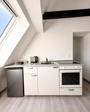 Eine moderne Küche mit eingebautem Geschirrspüler, Backofen und einem großen Fenster für viel Tageslicht.