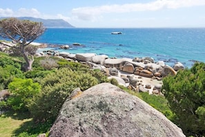 Un paisaje costero con grandes rocas, vegetación y vista al mar.