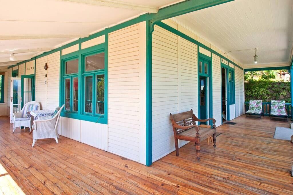 Un portico coperto con pavimento in legno, pareti bianche con dettagli color acquamarina e mobili in vimini.