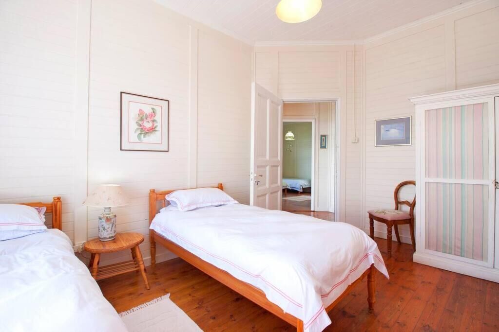 A bedroom with two single beds, a wooden chair, a small table with a lamp, and a wardrobe.