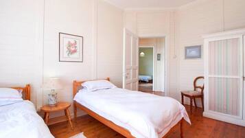 A bedroom with two single beds, a wooden chair, a small table with a lamp, and a wardrobe.