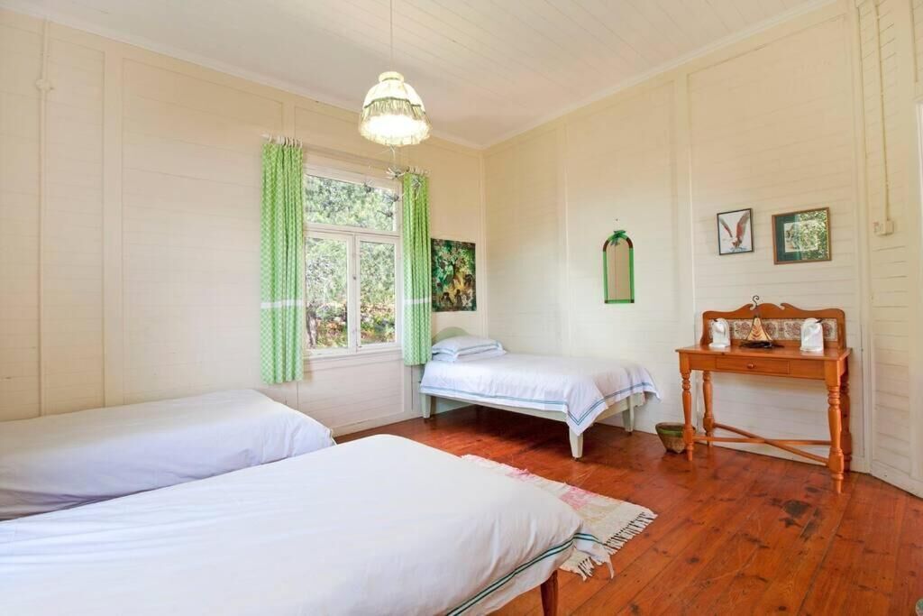 Une chambre avec deux lits, une table en bois et une fenêtre avec des rideaux.