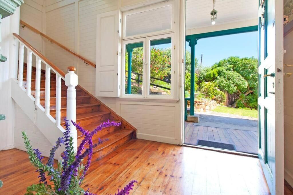 A wooden staircase with white railings leading to a room with a view of a garden through a glass door.