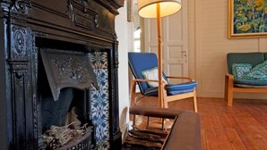 A room with a fireplace, a blue armchair, a wooden floor, and a painting on the wall. - Stunning Boulders Beach house  (Simons Town, Cape Town)