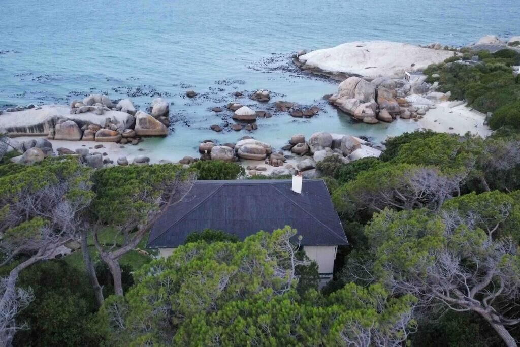 A coastal property with a house surrounded by large rocks and trees.
