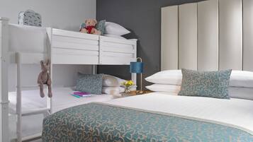 Une chambre avec des lits superposés, une table de chevet avec une lampe et des coussins décoratifs.