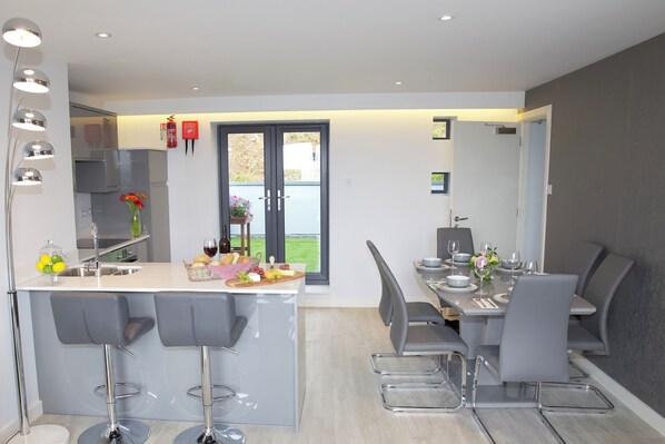A modern kitchen with a central island, bar stools, and a dining area with a table set for four.