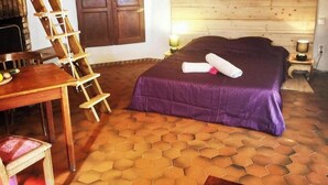A room with a wooden ladder, a bed with a purple bedspread, and a table with a chair. - A cozy and unique patio overlooking the ocean (FITOU)