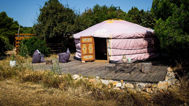 A traditional yurt with a wooden deck, a small table, and a bench. - Yurt facing the ocean, surrounded by nature (FITOU)