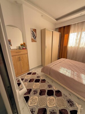 A bedroom with a bed, a wardrobe, a mirror, and a patterned floor. - Private Apartment in Hurghada (Égypte hurgada)