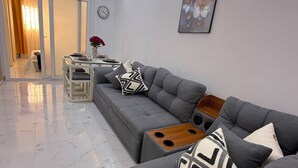 Una sala de estar moderna con un sofá gris, una mesa de centro de madera y un cuadro en la pared.